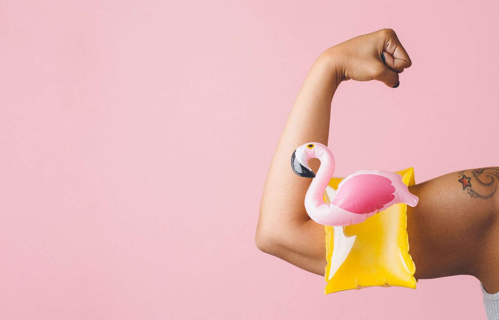 curled bicep wearing a flamingo pool toy