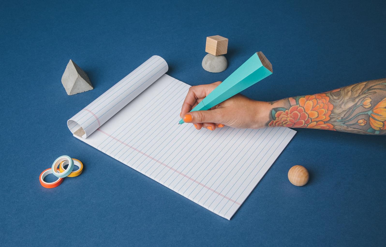 Hand mit einem großen blauen Stift auf einem Block 